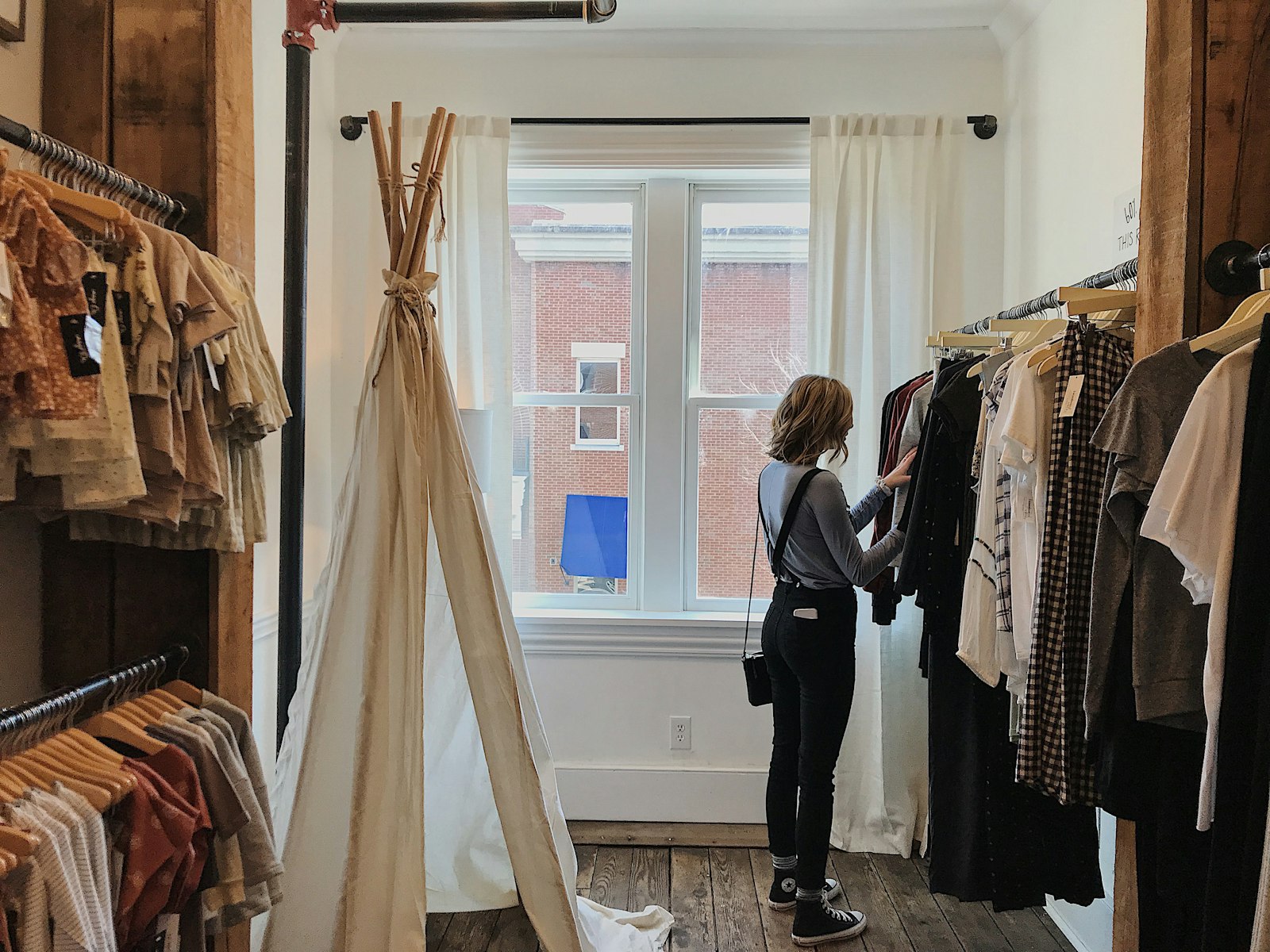 A shopper browsing clothes in a bright boutique